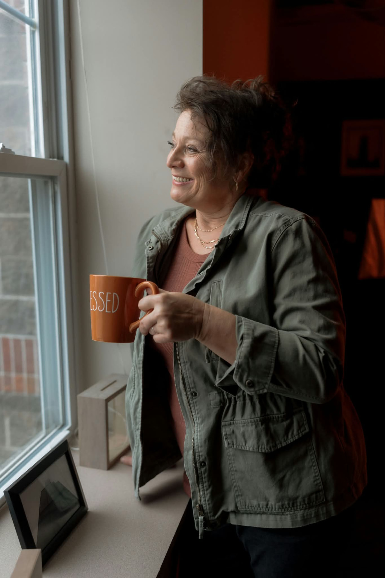 Dr. Karen holding a mug by a window